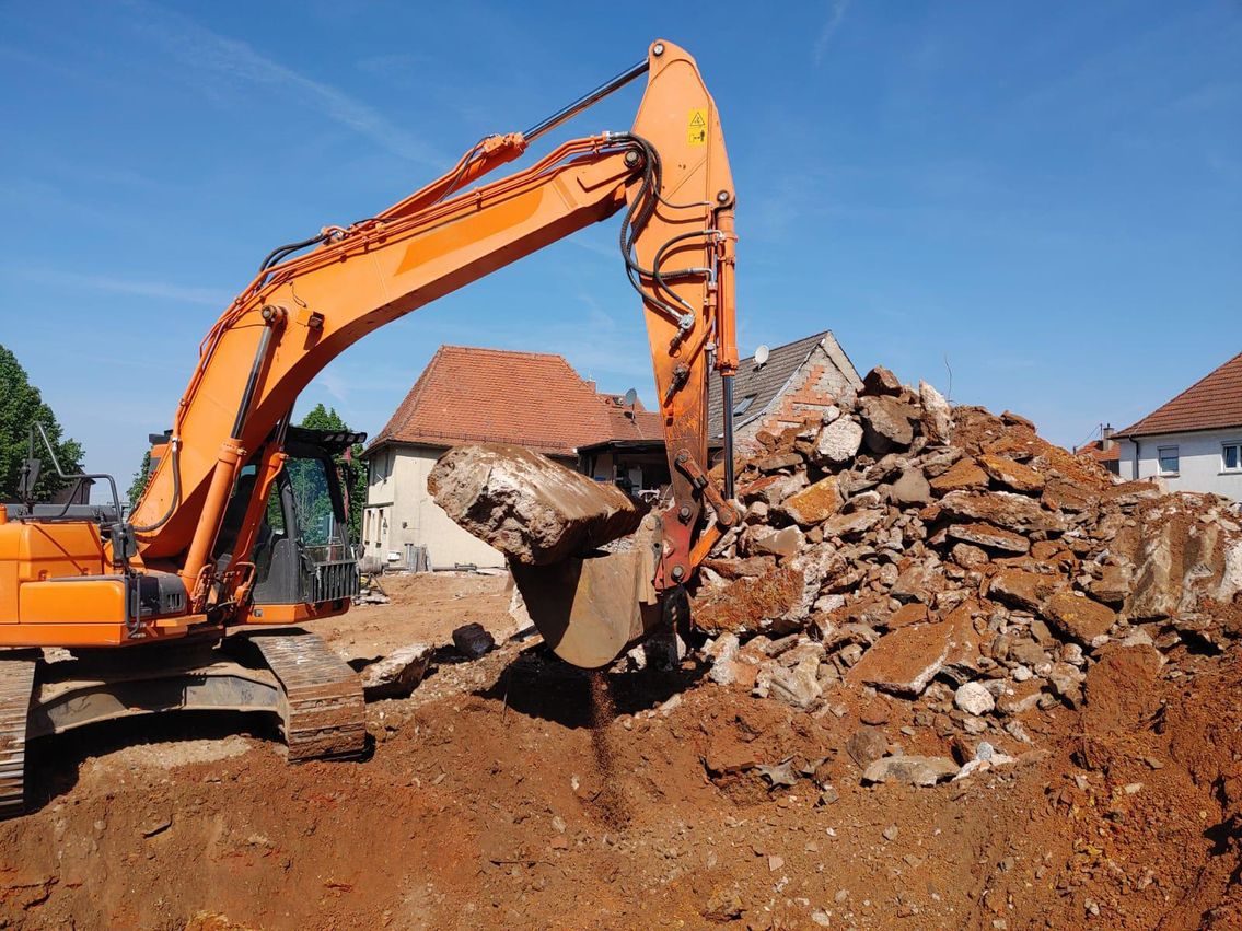 Bagger mit Schaufel räumt Bauschutt weg